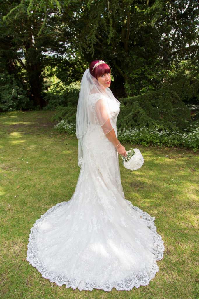 Bride with her bouquet stood in the gardens at The Oaklands Hotel in Norwich